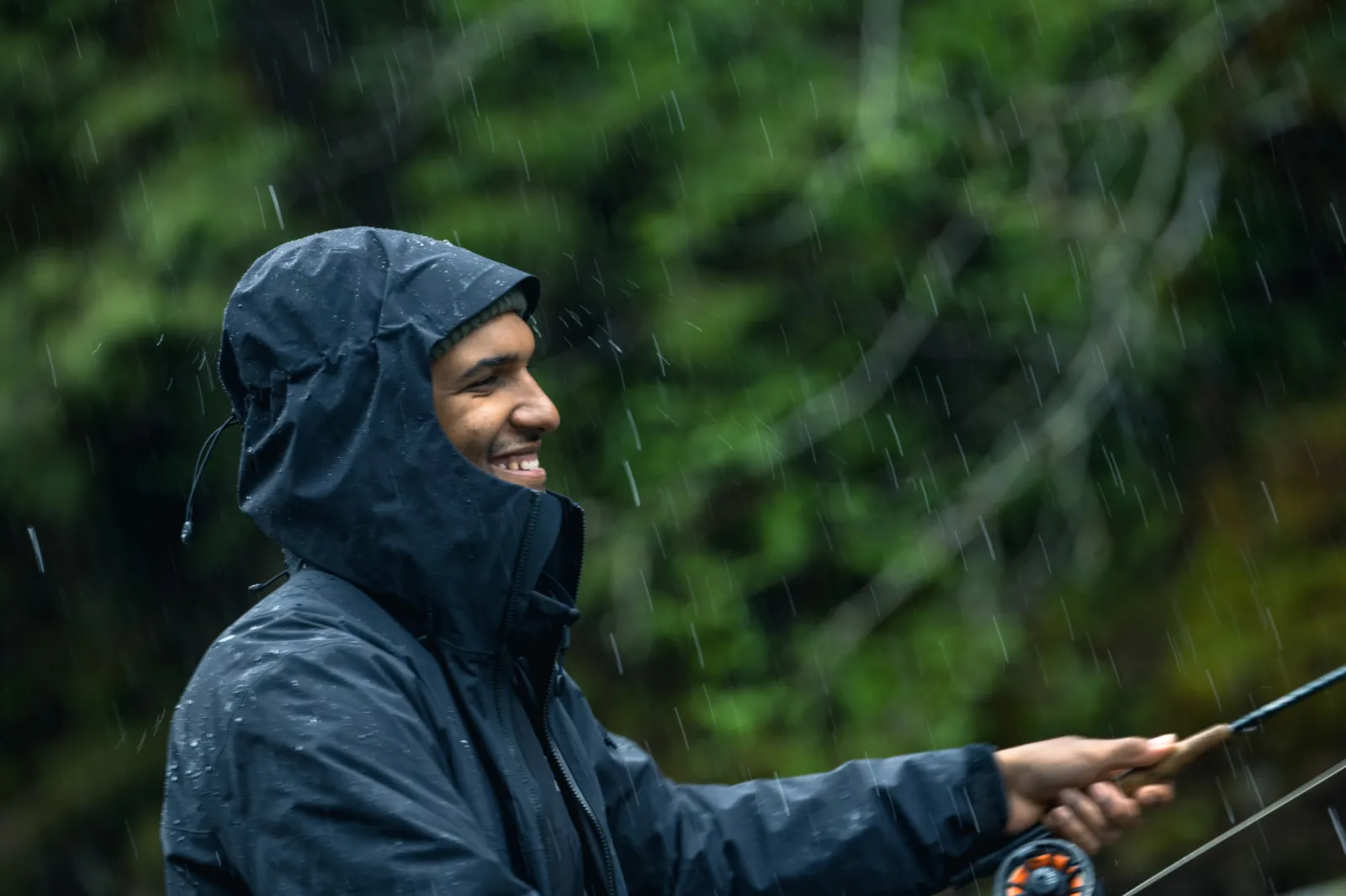A man smiling while fishing in the rain