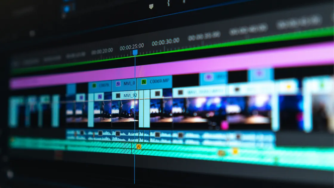 Video editing timeline with colorful tracks and clips on a screen.