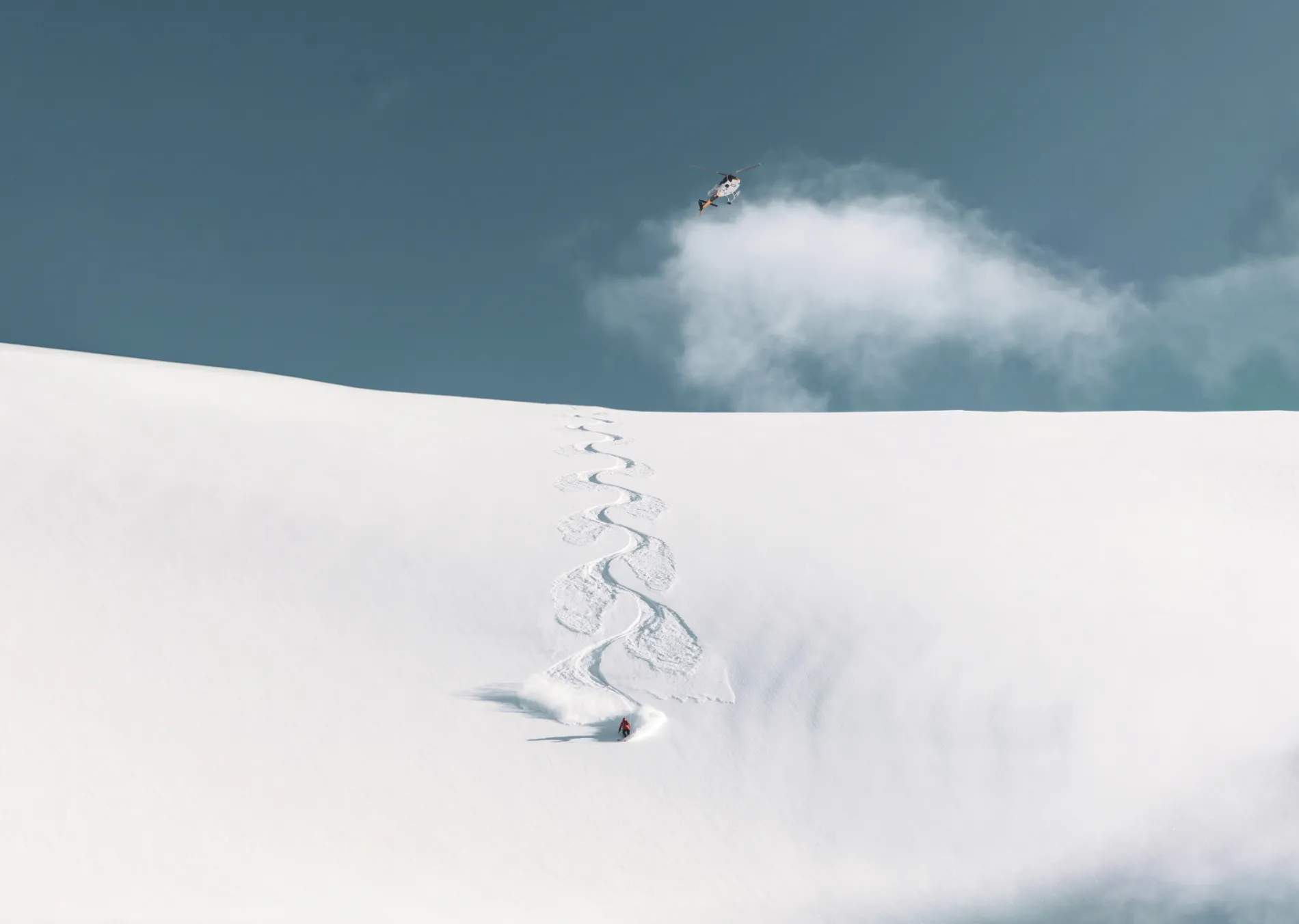 A person skiing with a helicopter in the background